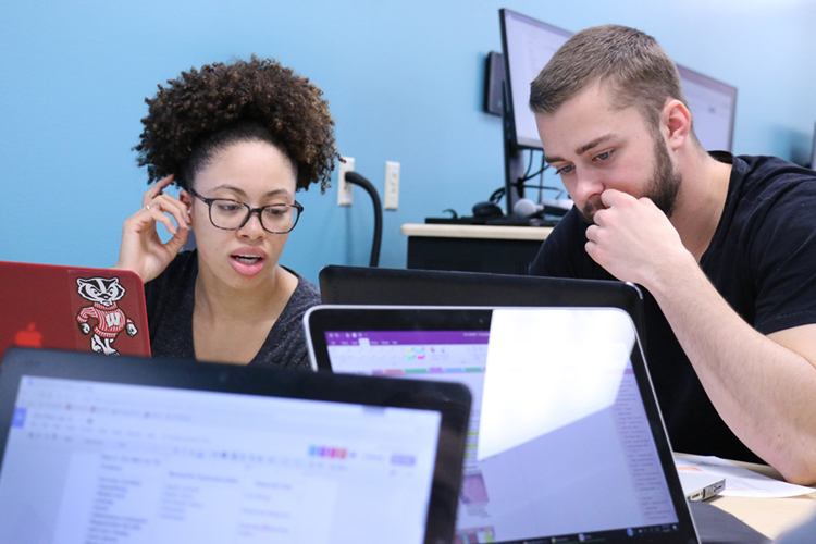 Two students, a women and man, looking at their laptop computers.