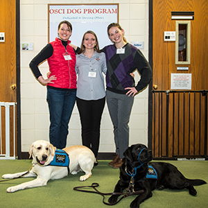 3 young veterinarian students pose with two service dogs