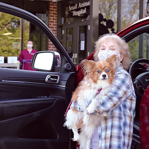 women holds her dog on way into hospital