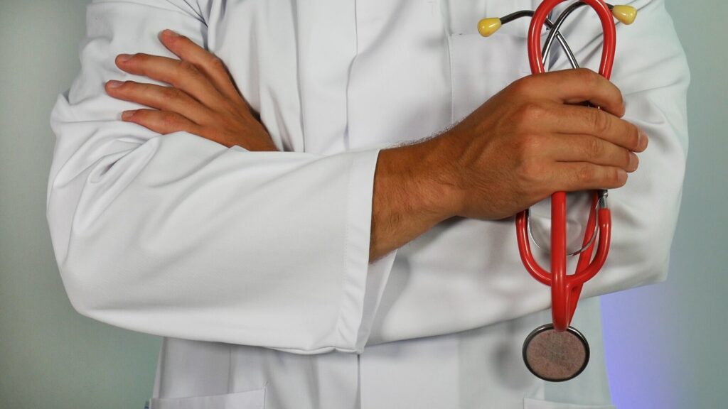 person in white coat holding stethoscope