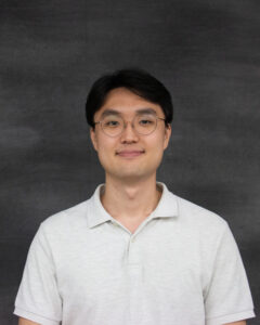 A short dark hair man with glasses wearing a light grey polo shirt. Brian Park