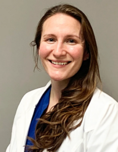 Long brown hair woman wearing a blue shirt with white doctor's coat. Melissa Hayes
