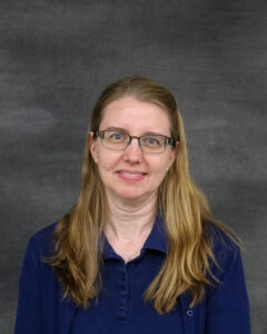 A long sandy blonde hair woman wearing a navy polo shirt. Jessica Gunby