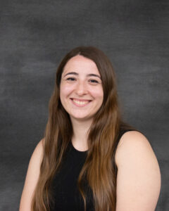 A long brown hair woman wearing sleeveless black top. Marta Bakaj
