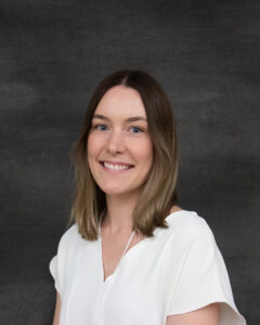 A long brown hair woman wearing white short sleeve blouse. Megan Strong