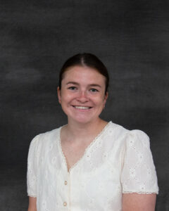 A woman with dark, pulled back hair wearing a short sleeve white blouse. Morgan Sliger