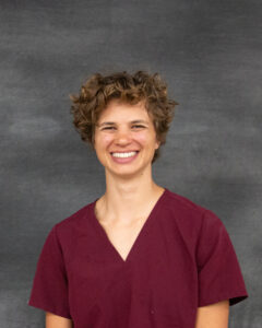 A short curly brown hair woman with burgundy scrub top. Rachel Illgen